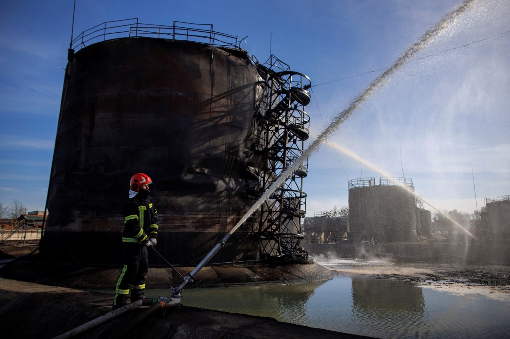 Brandweerlieden werken aan een beschadigd oliedepot na een Russische raketaanval in de stad Lviv, Oekraïne op 27 maart 2022.