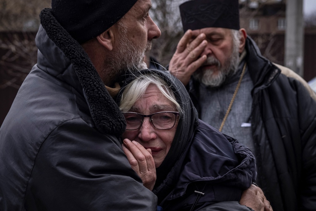 Familieleden van een burger wiens lichaam werd opgegraven uit zijn tuin, reageren op 12 april 2022 in het dorp Gostomel in de regio Kiev. 