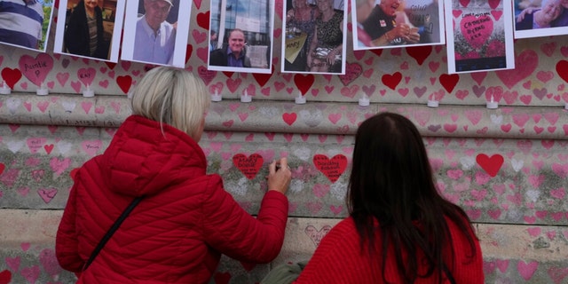 BESTAND - Familieleden schrijven dinsdag 29 maart 2022 een brief aan twee zussen die zijn overleden aan COVID op de National Covid Memorial Wall in Londen. Uit de laatste cijfers van het Britse bureau voor de statistiek blijkt dat de verspreiding van COVID-19 in het VK heeft bereikt recordniveaus, zoals ze aangeven Naar schatting heeft 1 op de 13 mensen de afgelopen week het virus opgelopen.  Naar schatting 4,9 miljoen mensen hebben het virus opgelopen in de week die eindigde op 26 maart, zei het Office for National Statistics op vrijdag 1 april 2022, een stijging van 4,3 miljoen in de voorgaande week. 