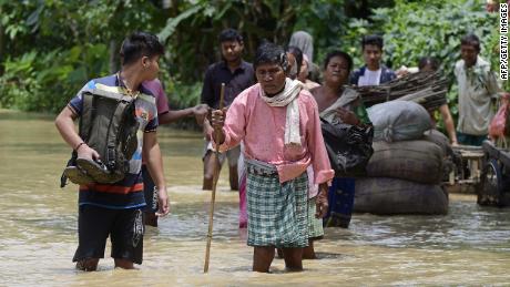 Mensen lopen op 18 mei in het overstromingswater in het Nagoon-district van de Indiase staat Assam.