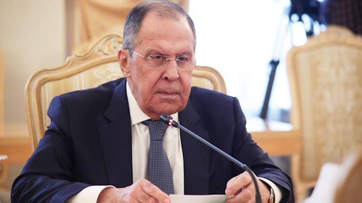 Minister van Buitenlandse Zaken Sergey Lavrov staart strak naar een (onzichtbare) gesprekspartner aan een vergadertafel, voor de microfoon.