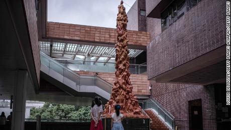twee kinderen kijken naar "  pijler van schaamte "  Een standbeeld op de campus van de Universiteit van Hong Kong op 15 oktober 2021 in Hong Kong.