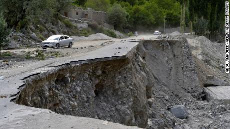 A car drives through a partially collapsed section of Pakistan's Karakoram Expressway, which was damaged after a glacial lake exploded in the Gilgit-Baltistan region.
