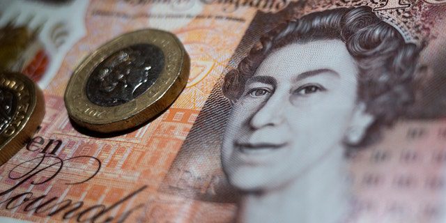 Britse munt van twee pond bovenop een bankbiljet van 10 pond met het portret van koningin Elizabeth II.
