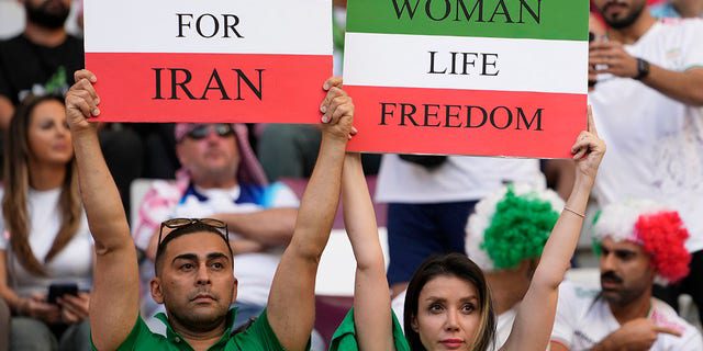 Iraanse voetbalfans houden spandoeken vast waarop te lezen is 