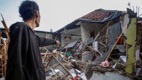 Seorang pria berdiri di samping rumah yang rusak pascagempa yang melanda Cianjur, Provinsi Jawa Barat, Indonesia pada 21 November 2022.