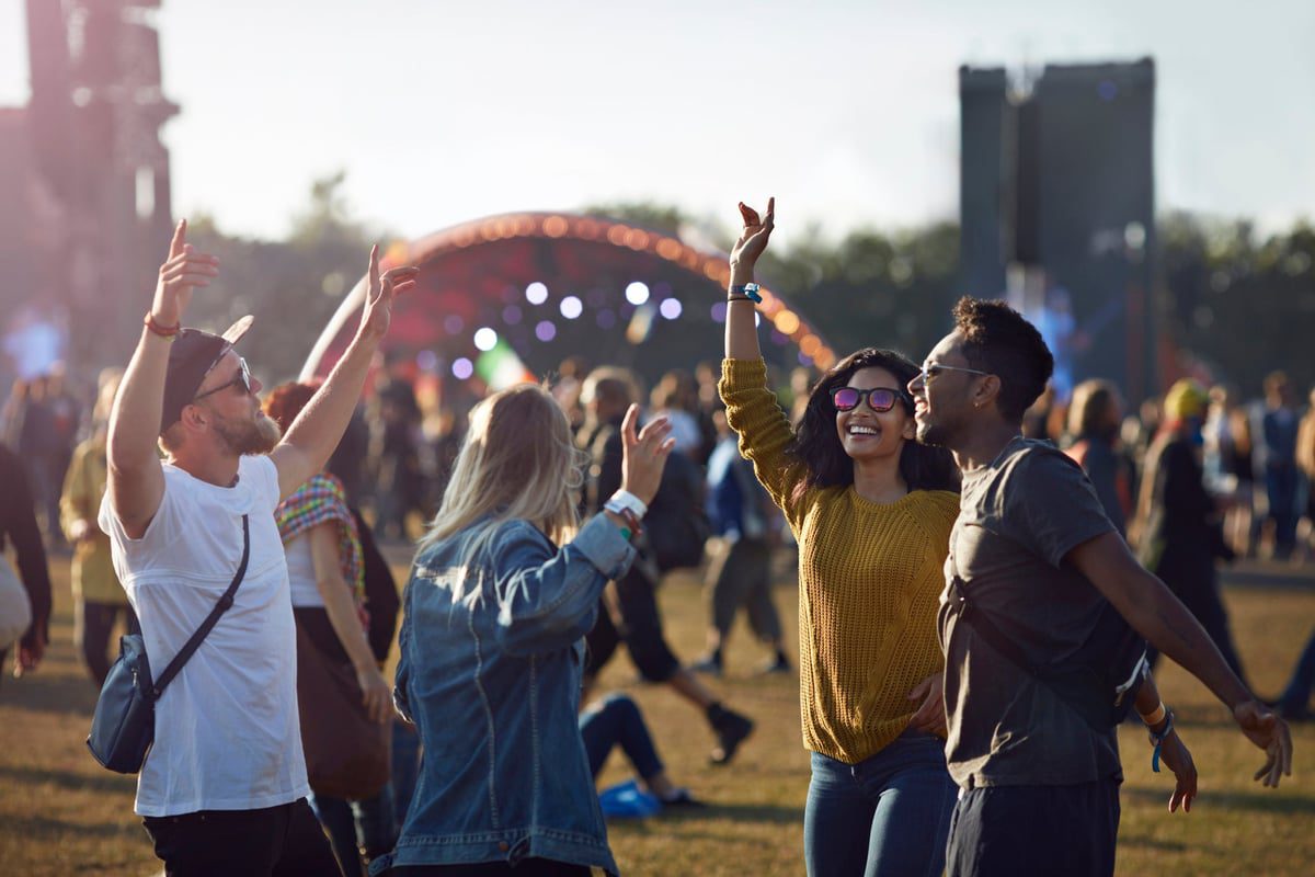 Groep vrienden dansen in de menigte terwijl ze op het podium van een muziekfestival lopen.
